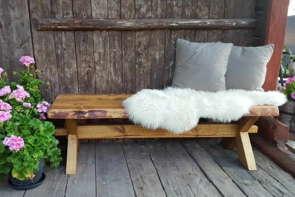 Klassisk kryssbänk från Nordanlids Rustik i massivt trä, där tappen sammanfogar kryssbenen och hålls fast med en kil. Okantad framsida där trädets naturliga form har sparats.